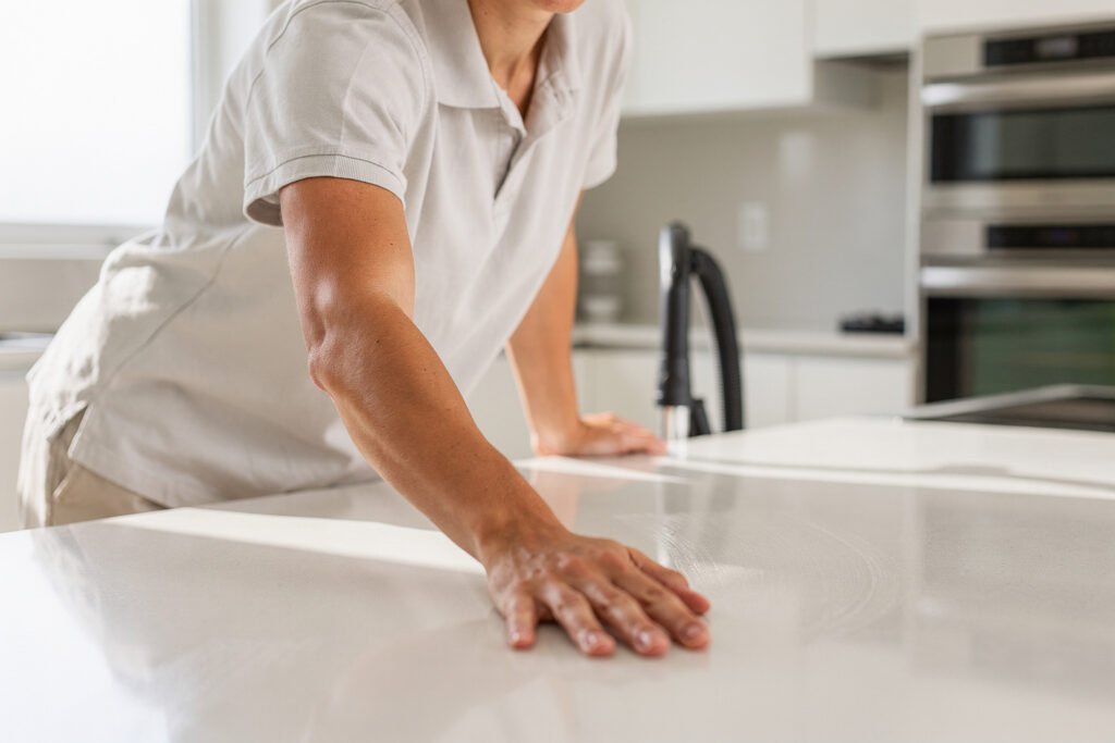 Cleaner finishing a deep clean of a bright kitchen